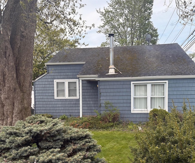back of house with a lawn and roof with shingles