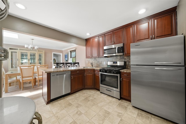 96 Pardee Ave, Islip, NY 11751 - kitchen featuring appliances with stainless steel finishes, a peninsula, tasteful backsplash, a chandelier, and light stone counters