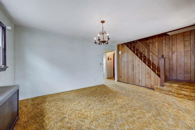 unfurnished living room featuring stairs, wood walls, and carpet