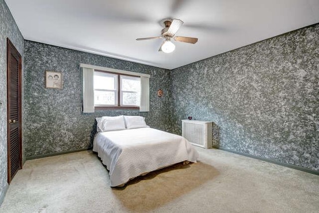 carpeted bedroom with a ceiling fan and wallpapered walls