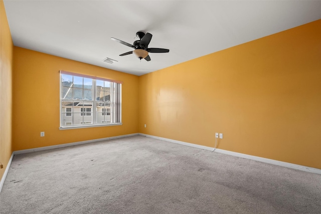 carpeted spare room featuring baseboards, ceiling fan, and visible vents