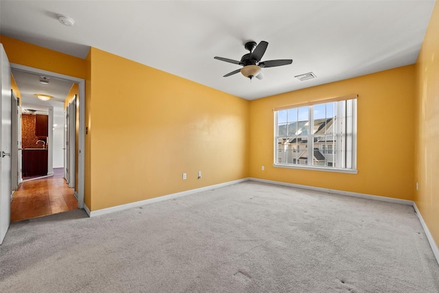 carpeted empty room featuring baseboards, a ceiling fan, and visible vents