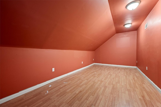 bonus room featuring baseboards, visible vents, lofted ceiling, and light wood-style floors