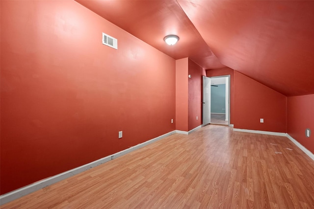 bonus room featuring visible vents, baseboards, wood finished floors, and vaulted ceiling