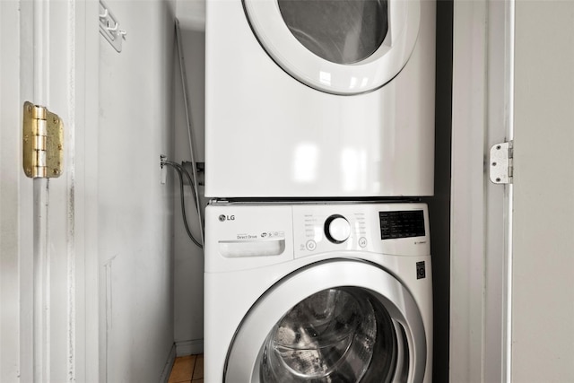 laundry area with laundry area, tile patterned flooring, baseboards, and stacked washer / drying machine
