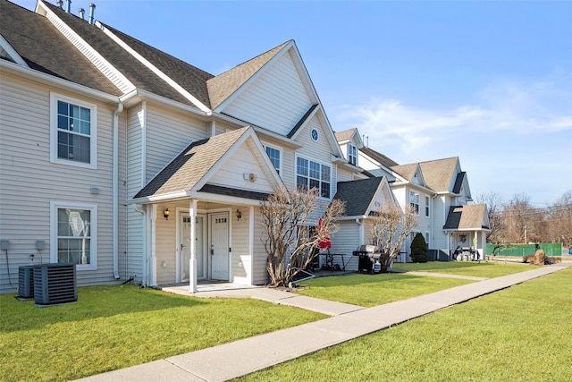 view of front of property featuring a front lawn, roof with shingles, and a residential view