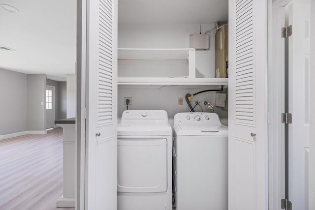 laundry room featuring laundry area, visible vents, baseboards, washing machine and clothes dryer, and light wood-style flooring