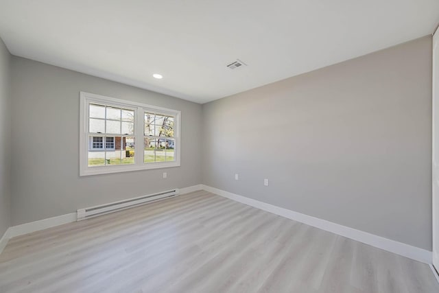 empty room featuring visible vents, baseboards, light wood-style floors, and a baseboard heating unit