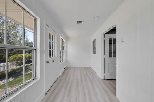 hallway with baseboards, baseboard heating, light wood-type flooring, and visible vents