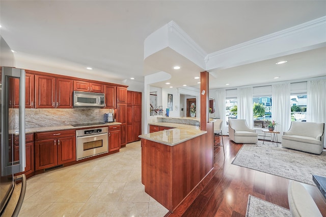 86 Jefferson Ave, Island Park, NY 11558 - kitchen with ornamental molding, open floor plan, light stone counters, backsplash, and stainless steel appliances