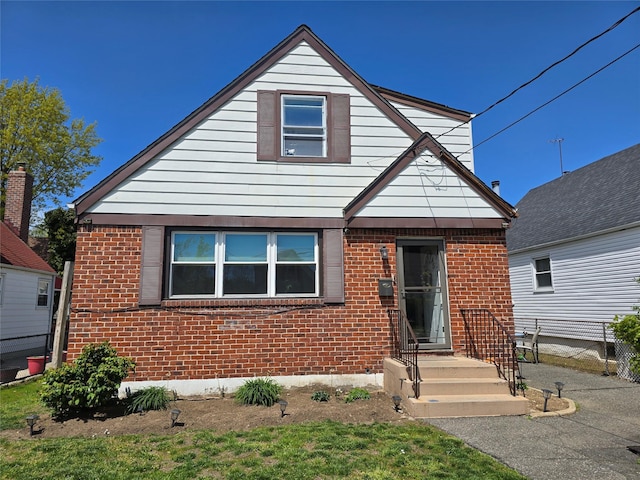bungalow featuring brick siding and fence