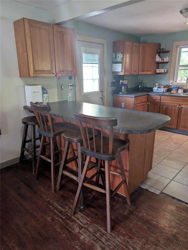 kitchen featuring dark countertops, a kitchen breakfast bar, light wood finished floors, and a peninsula