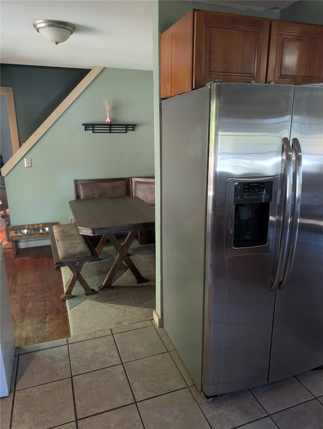 kitchen with stainless steel fridge, brown cabinets, and light tile patterned flooring