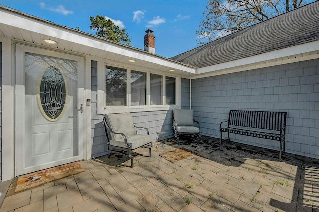 203 N Coleman Rd, Centereach, NY 11720 - entrance to property featuring roof with shingles, a chimney, and a patio