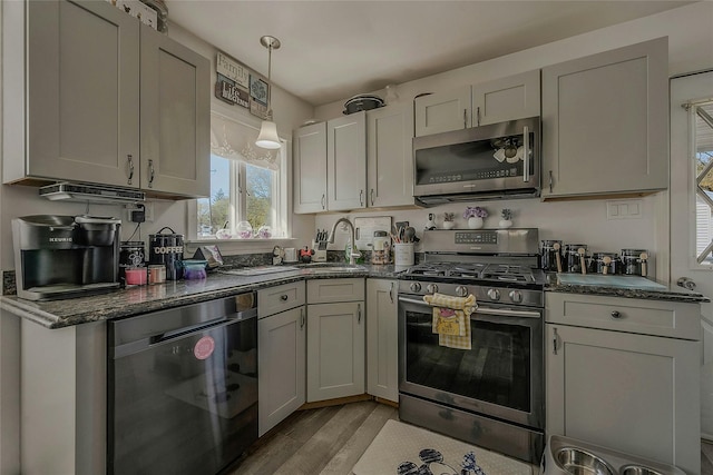 203 N Coleman Rd, Centereach, NY 11720 - kitchen with stainless steel appliances, a sink, light wood-type flooring, dark stone countertops, and decorative light fixtures