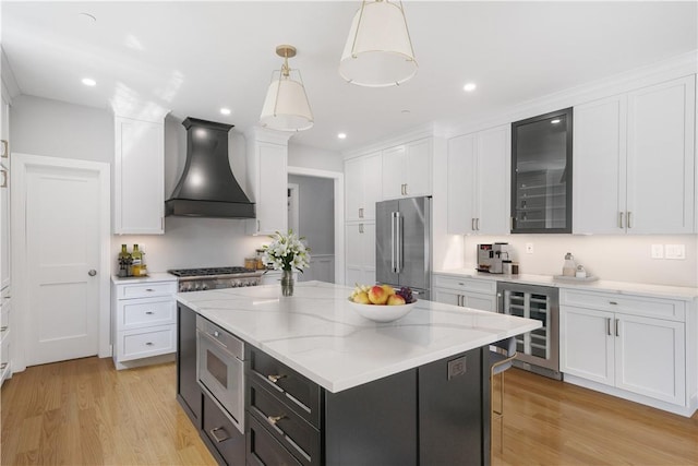 kitchen featuring beverage cooler, white cabinets, custom range hood, decorative light fixtures, and stainless steel appliances