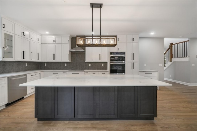 kitchen with light wood-style floors, decorative backsplash, white cabinetry, and stainless steel appliances