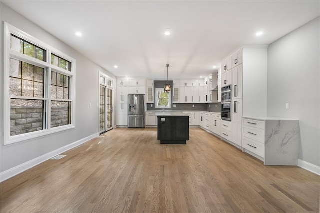 kitchen featuring baseboards, a kitchen island, stainless steel appliances, and light wood-type flooring