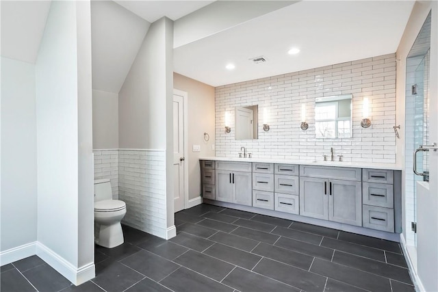 bathroom featuring a sink, tile patterned flooring, double vanity, tile walls, and visible vents