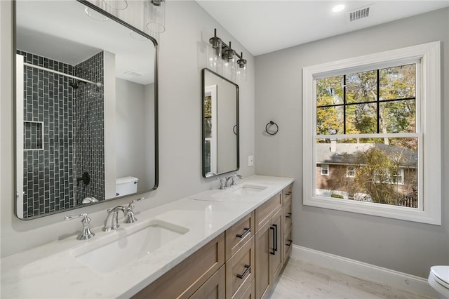 bathroom with toilet, visible vents, a healthy amount of sunlight, and a sink