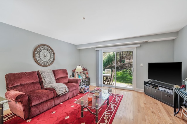 living room featuring baseboards, visible vents, and light wood-type flooring