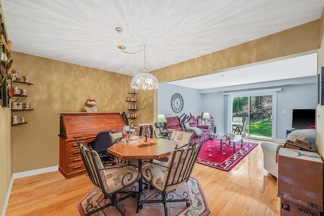 dining area with baseboards, a chandelier, and light wood-style floors