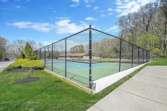 view of tennis court with fence and a yard