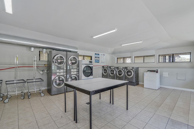 playroom featuring tile patterned floors, baseboards, stacked washer and dryer, and washer and dryer