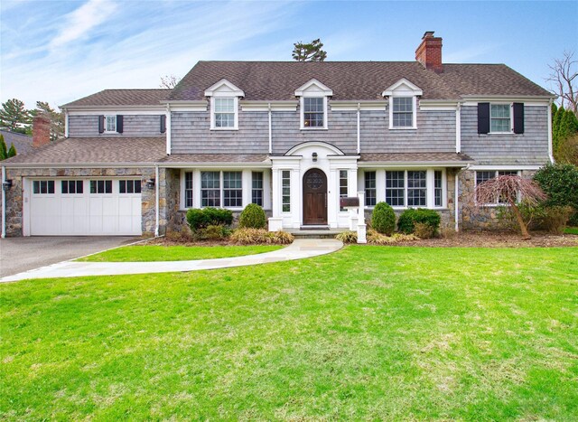 52 Northwoods Rd, Manhasset, NY 11030 - view of front of house with a chimney, stone siding, driveway, a front lawn, and an attached garage