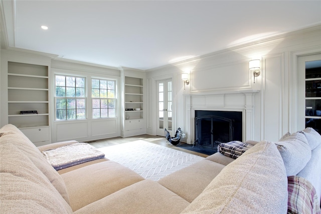52 Northwoods Rd, Manhasset, NY 11030 - living area with ornamental molding, built in shelves, a fireplace with flush hearth, wood finished floors, and a decorative wall