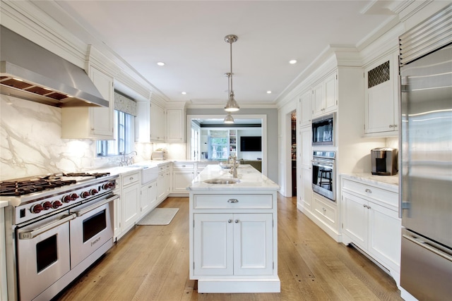 52 Northwoods Rd, Manhasset, NY 11030 - kitchen with built in appliances, wall chimney range hood, a sink, ornamental molding, and a kitchen island with sink