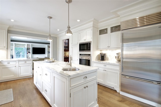 52 Northwoods Rd, Manhasset, NY 11030 - kitchen with built in appliances, a sink, a kitchen island with sink, white cabinetry, and crown molding