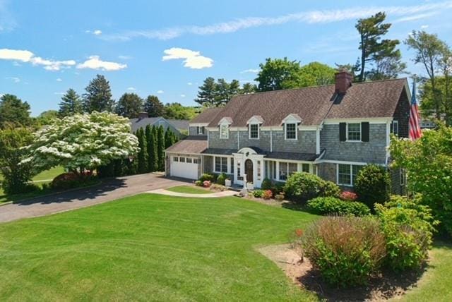 52 Northwoods Rd, Manhasset, NY 11030 - view of front of house featuring concrete driveway, a front lawn, a chimney, and an attached garage