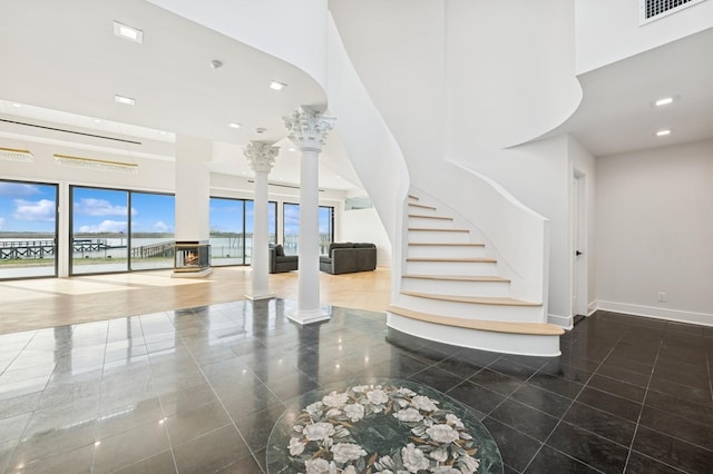 staircase with baseboards, a high ceiling, decorative columns, and visible vents