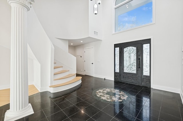 entrance foyer with stairway, decorative columns, granite finish floor, and a towering ceiling