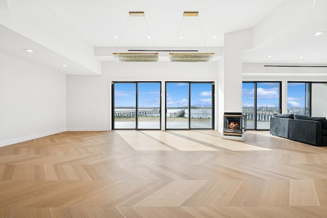 unfurnished living room featuring baseboards, a high ceiling, and a healthy amount of sunlight