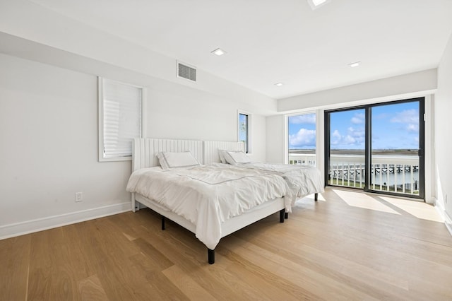 bedroom featuring access to outside, baseboards, visible vents, and wood finished floors