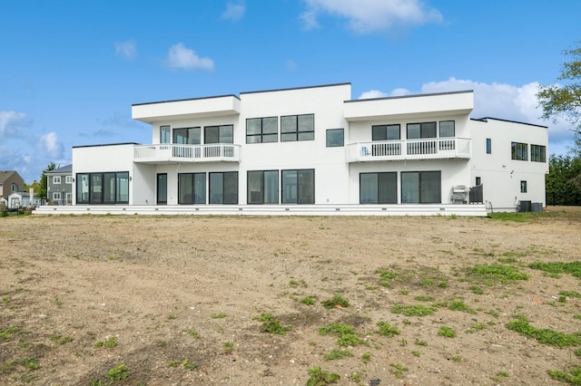 rear view of property featuring central air condition unit, a balcony, and stucco siding