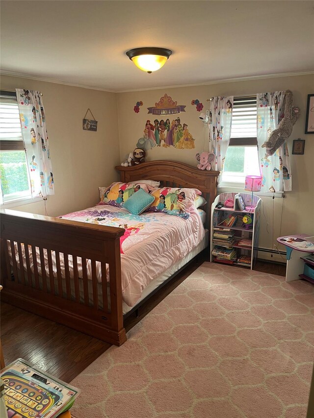 bedroom featuring crown molding, a baseboard heating unit, and wood finished floors