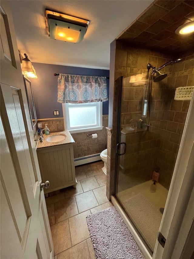 full bath with baseboard heating, a shower stall, vanity, a wainscoted wall, and toilet