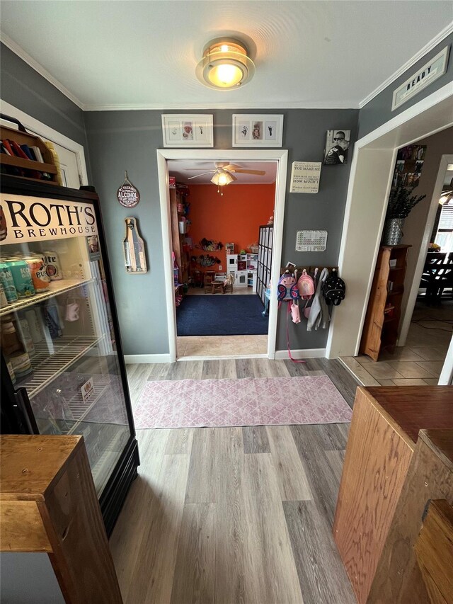 foyer entrance with crown molding, a ceiling fan, and wood finished floors
