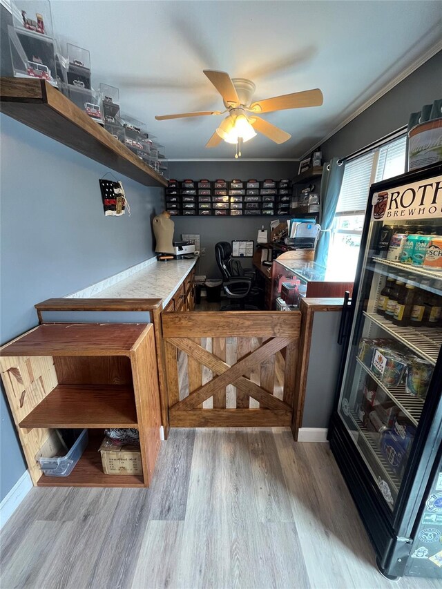 interior space with built in study area, a ceiling fan, wood finished floors, and ornamental molding