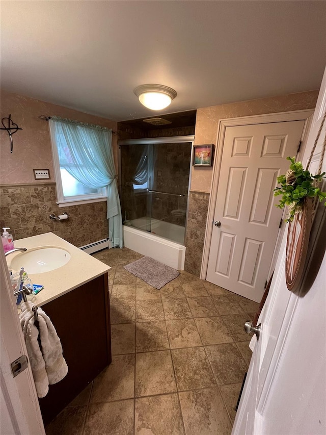 bathroom featuring vanity, a baseboard radiator, shower / bath combination with glass door, and tile walls