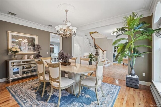 dining space featuring visible vents, baseboard heating, an inviting chandelier, ornamental molding, and stairs