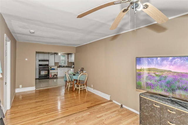 dining space featuring light wood finished floors, baseboards, and ceiling fan