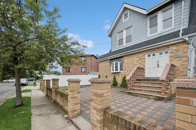 31-50 Buell, East Elmhurst, NY 11369 - view of front of home with entry steps, brick siding, fence, and roof with shingles
