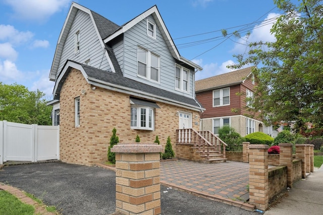 31-50 Buell, East Elmhurst, NY 11369 - view of front of home featuring a patio area, roof with shingles, brick siding, and fence