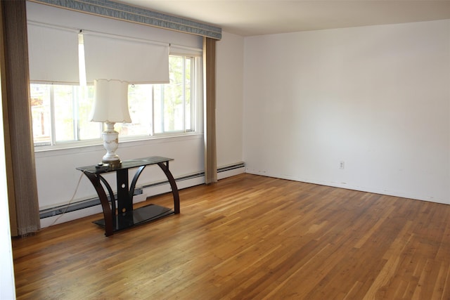 unfurnished room featuring baseboard heating and wood finished floors