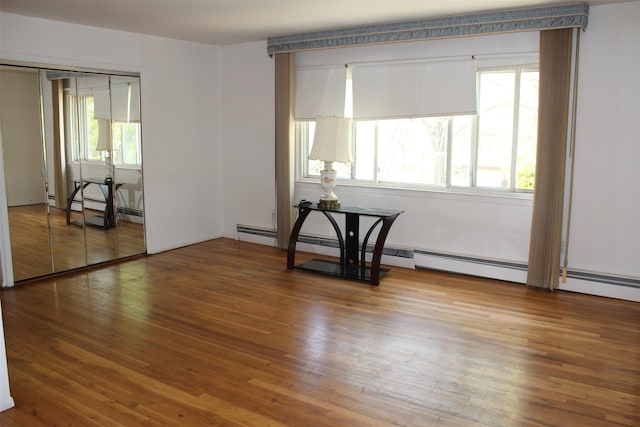 spare room featuring baseboard heating and wood finished floors