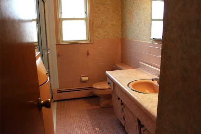 bathroom with a wainscoted wall, baseboard heating, wallpapered walls, and tile walls